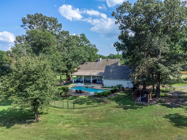 back of property featuring a lawn, a patio area, and a fenced in pool