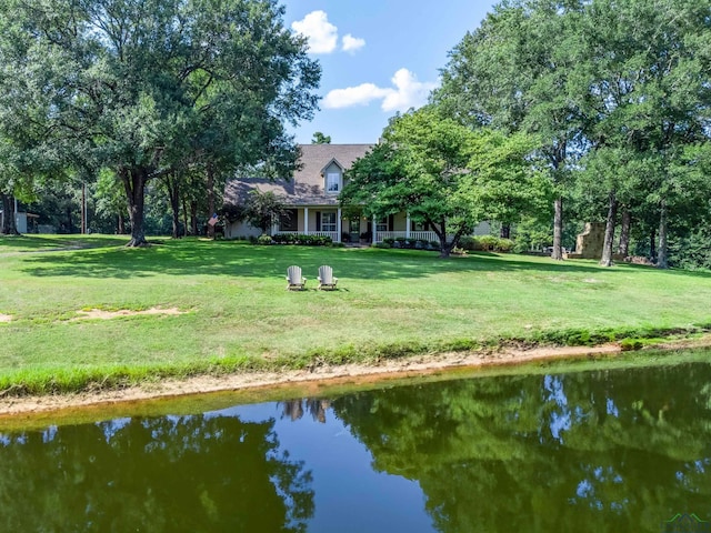 back of property featuring a water view and a lawn