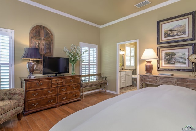 bedroom with crown molding, light hardwood / wood-style flooring, and ensuite bath