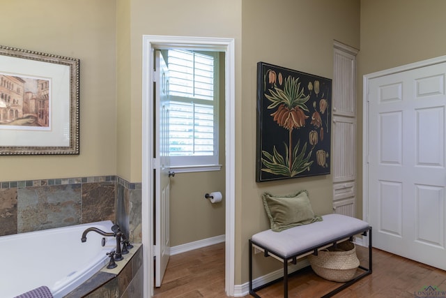 bathroom featuring a relaxing tiled tub, a healthy amount of sunlight, and wood-type flooring