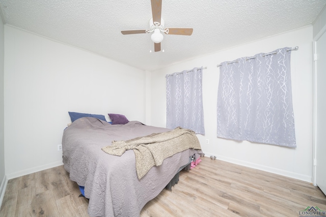 bedroom featuring ceiling fan, light hardwood / wood-style floors, and a textured ceiling