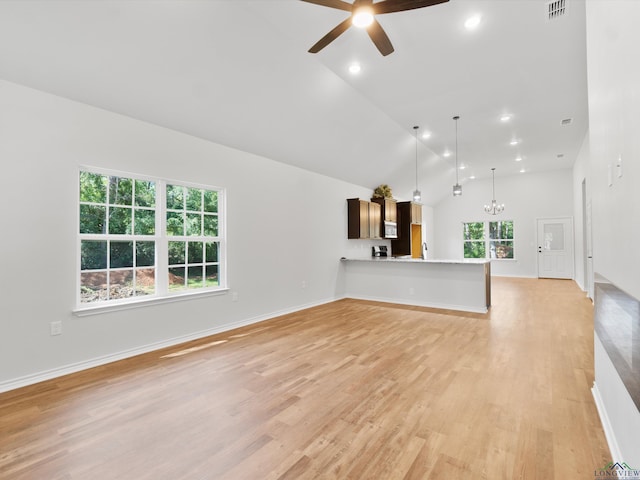 unfurnished living room with light hardwood / wood-style flooring, high vaulted ceiling, and ceiling fan with notable chandelier