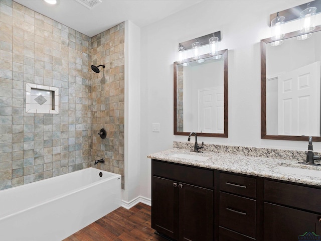 bathroom featuring vanity, wood-type flooring, and tiled shower / bath