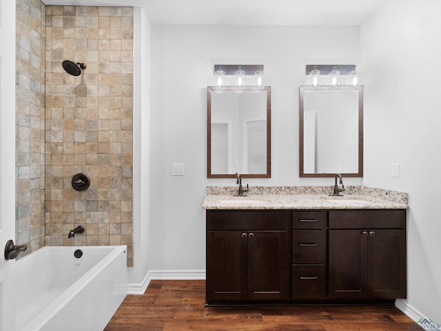 bathroom featuring hardwood / wood-style floors, vanity, and tiled shower / bath combo