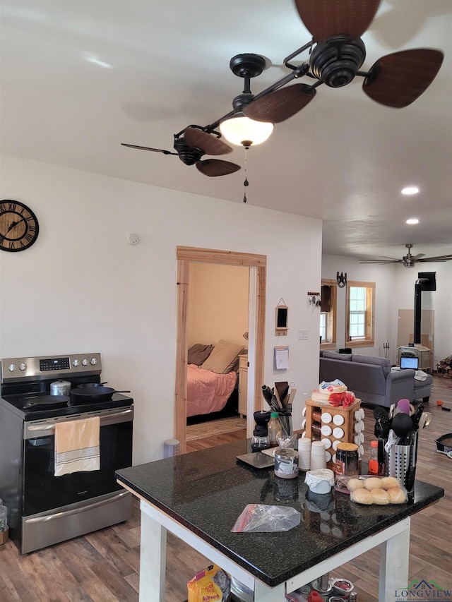 dining space with a wood stove, wood finished floors, and a ceiling fan