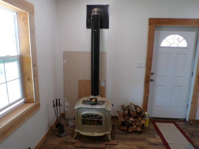 entryway with a wood stove, baseboards, and wood finished floors