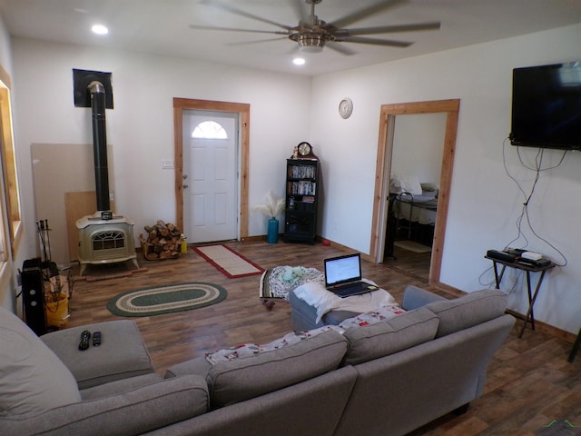 living room with a ceiling fan, recessed lighting, a wood stove, and wood finished floors