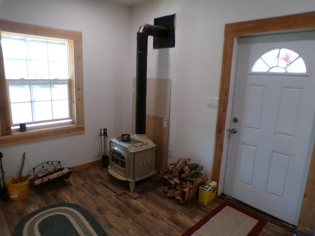 foyer entrance with a wood stove and wood finished floors