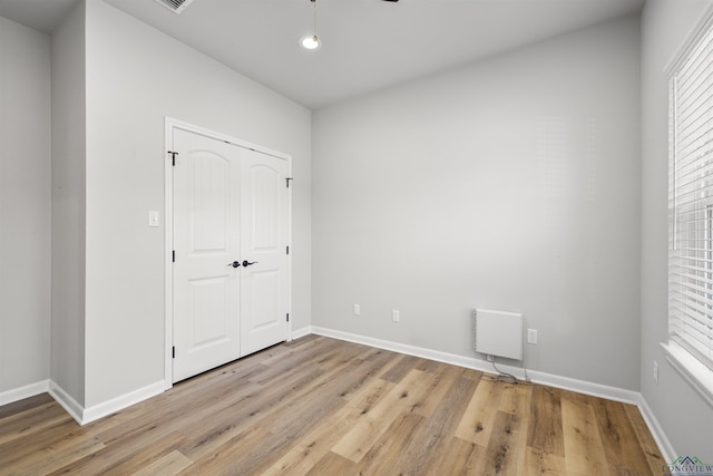 unfurnished bedroom featuring recessed lighting, baseboards, light wood-type flooring, and a closet