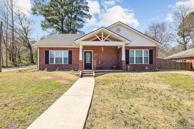 view of front of property featuring brick siding, covered porch, a front lawn, and fence