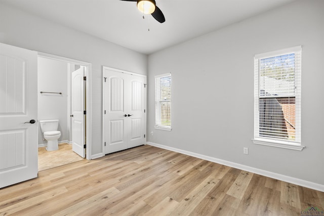 unfurnished bedroom featuring baseboards, multiple windows, and light wood-style flooring