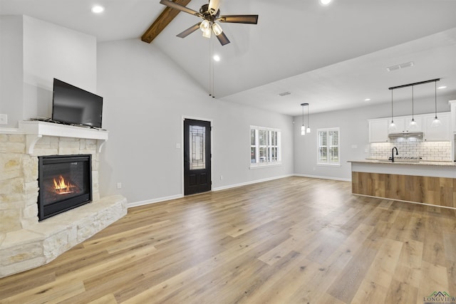 unfurnished living room with beam ceiling, a fireplace, visible vents, and light wood finished floors