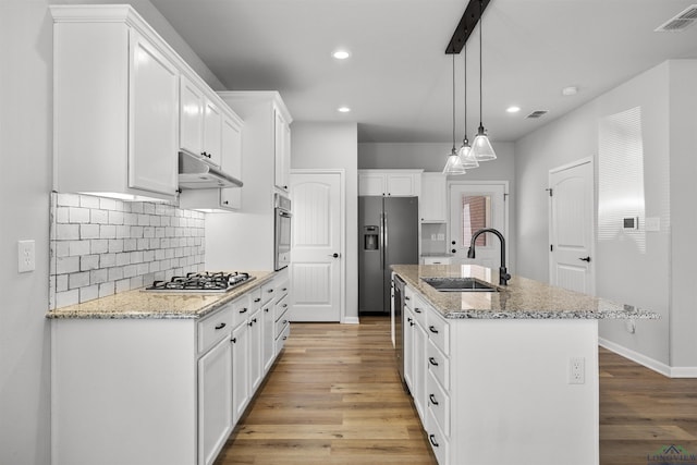 kitchen featuring visible vents, under cabinet range hood, white cabinets, stainless steel appliances, and a sink