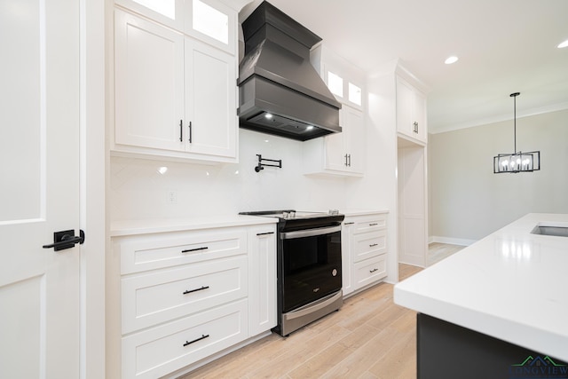 kitchen with light wood-type flooring, custom range hood, an inviting chandelier, white cabinetry, and stainless steel electric range