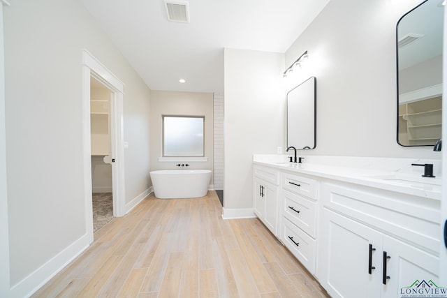 bathroom with a washtub, hardwood / wood-style floors, and vanity