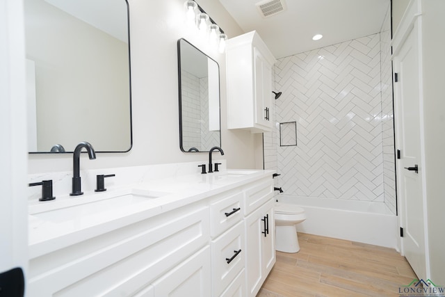 full bathroom with tiled shower / bath, hardwood / wood-style floors, vanity, and toilet