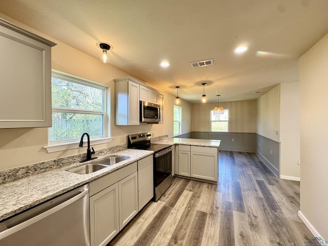 kitchen with visible vents, light wood-type flooring, appliances with stainless steel finishes, a peninsula, and a sink