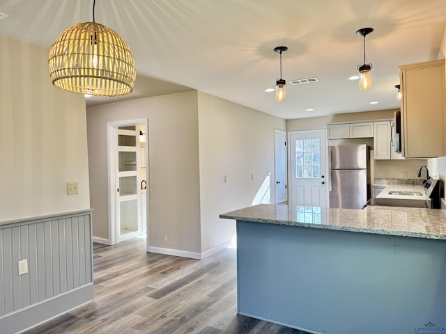 kitchen featuring light wood finished floors, visible vents, light stone counters, a peninsula, and stainless steel appliances