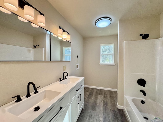 full bathroom featuring a sink, baseboards, wood finished floors, and washtub / shower combination