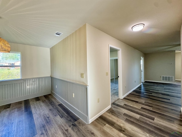 additional living space featuring visible vents, baseboards, a wainscoted wall, and wood finished floors