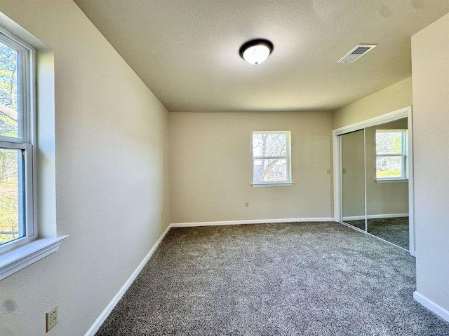 unfurnished bedroom featuring visible vents, baseboards, carpet flooring, a closet, and a textured ceiling