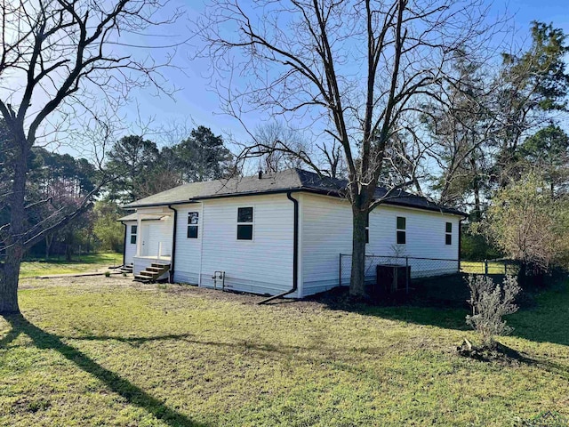 back of house featuring cooling unit, a lawn, and entry steps