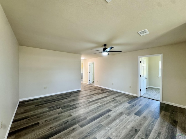 spare room featuring dark wood finished floors, visible vents, baseboards, and a ceiling fan