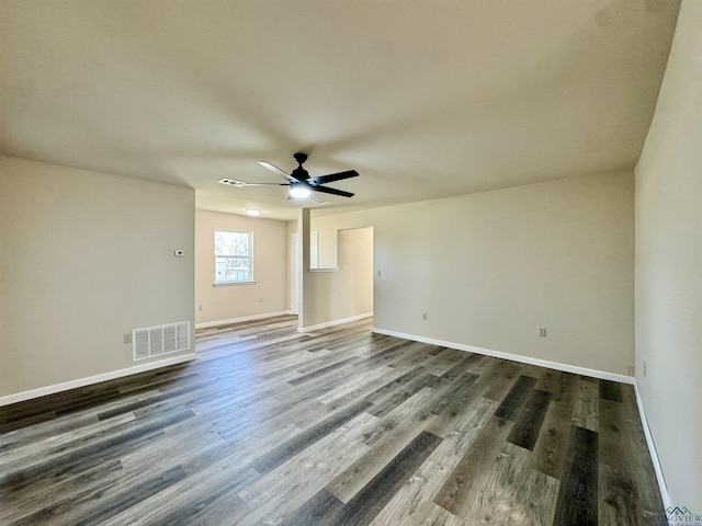 spare room featuring visible vents, baseboards, a ceiling fan, and dark wood-style flooring