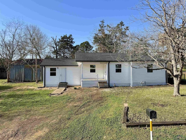 back of house featuring entry steps, a yard, fence, and a shingled roof