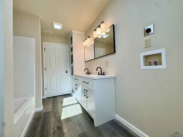 bathroom with visible vents, vanity, baseboards, and wood finished floors