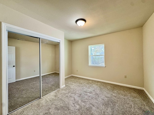 unfurnished bedroom featuring a closet, carpet flooring, a textured ceiling, and baseboards