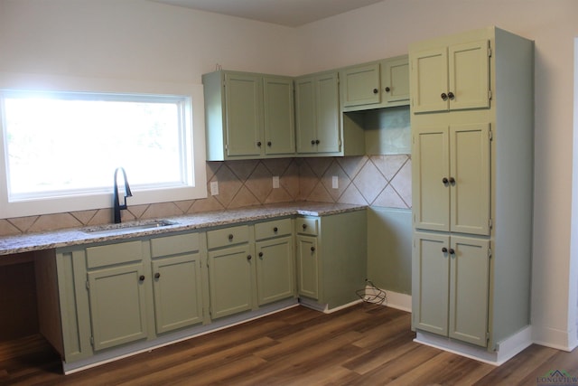 kitchen with light stone countertops, sink, tasteful backsplash, dark hardwood / wood-style flooring, and green cabinetry