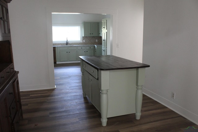 kitchen featuring a center island, sink, backsplash, and dark wood-type flooring