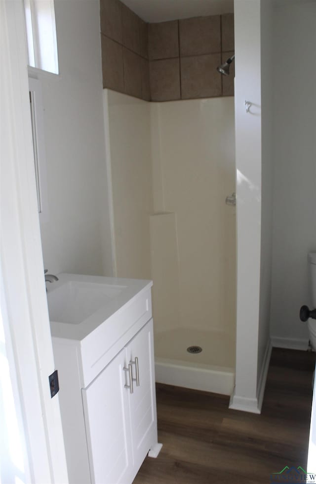 bathroom featuring a shower, wood-type flooring, vanity, and toilet