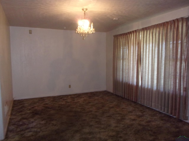 carpeted empty room with an inviting chandelier