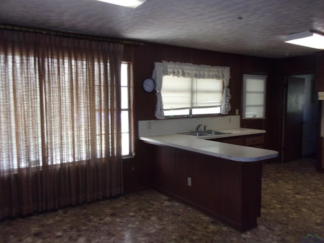 kitchen with kitchen peninsula, a textured ceiling, and sink