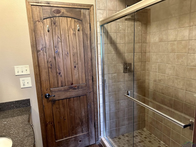 bathroom featuring a shower with door and vanity