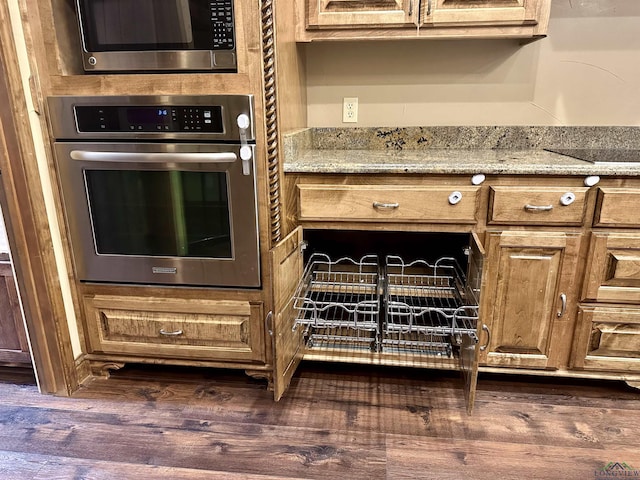 kitchen with light stone countertops, dark hardwood / wood-style floors, and appliances with stainless steel finishes