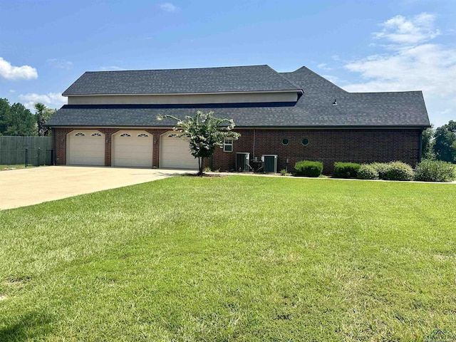 view of front of home with cooling unit, a front lawn, and a garage