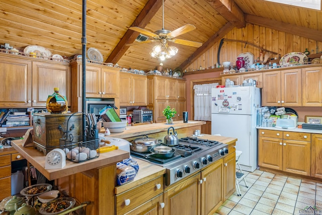 kitchen featuring ceiling fan, beam ceiling, white refrigerator, light tile patterned floors, and stainless steel gas stovetop