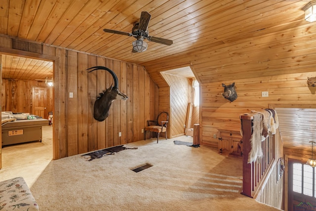 interior space featuring wood walls, light colored carpet, wood ceiling, and ceiling fan