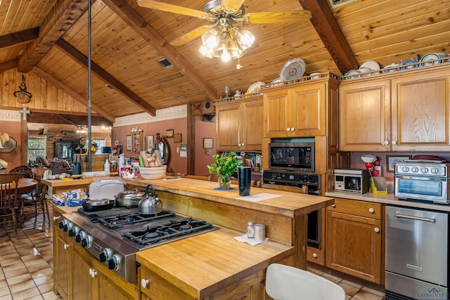 kitchen with wood counters, a center island, light tile patterned floors, and appliances with stainless steel finishes