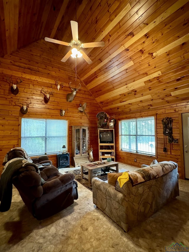 living room featuring wood walls, ceiling fan, a healthy amount of sunlight, and a wood stove