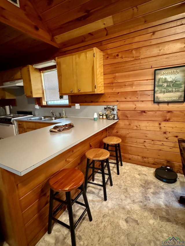 kitchen featuring kitchen peninsula, a kitchen breakfast bar, white range oven, and wooden walls