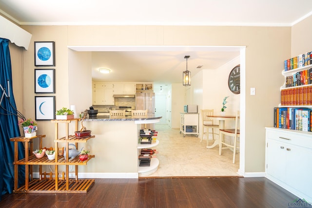 kitchen featuring pendant lighting, dark stone counters, dark hardwood / wood-style floors, ornamental molding, and kitchen peninsula