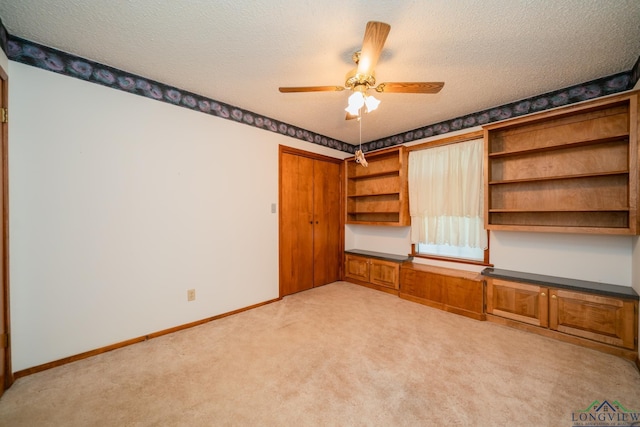 interior space featuring ceiling fan, light colored carpet, and a textured ceiling