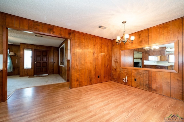 interior space featuring wooden walls, light hardwood / wood-style floors, and an inviting chandelier