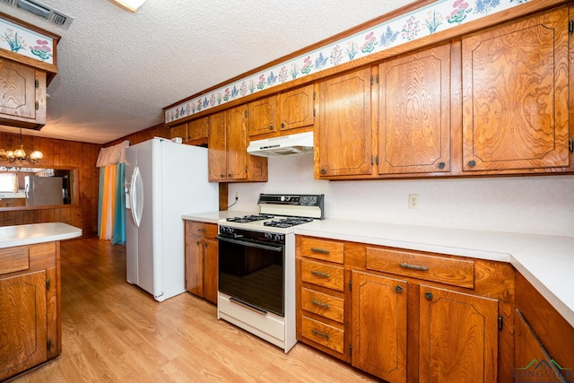 kitchen with light wood-type flooring, a textured ceiling, white appliances, and a notable chandelier