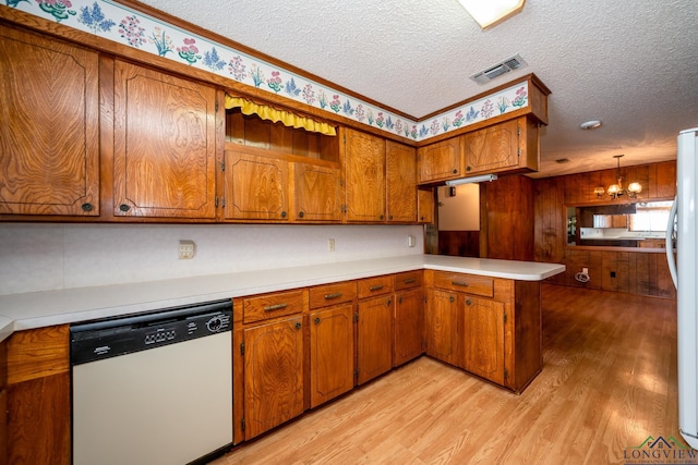 kitchen featuring hanging light fixtures, a chandelier, a textured ceiling, white appliances, and light hardwood / wood-style floors