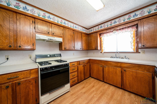 kitchen featuring light wood-type flooring, a textured ceiling, white gas range oven, and sink